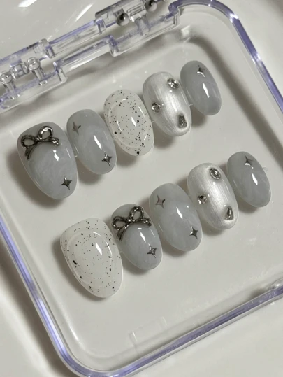 10片灰白椭圆形美甲贴片，饰有不规则艺术黑点、四角星、蝴蝶结和水钻，展现温柔清爽的气质，高端佩戴护甲，全可拆卸假指甲套装，适合上班族、学生、派对女孩以及所有季节的美甲用品，配备1瓶果冻胶和1把指甲锉。