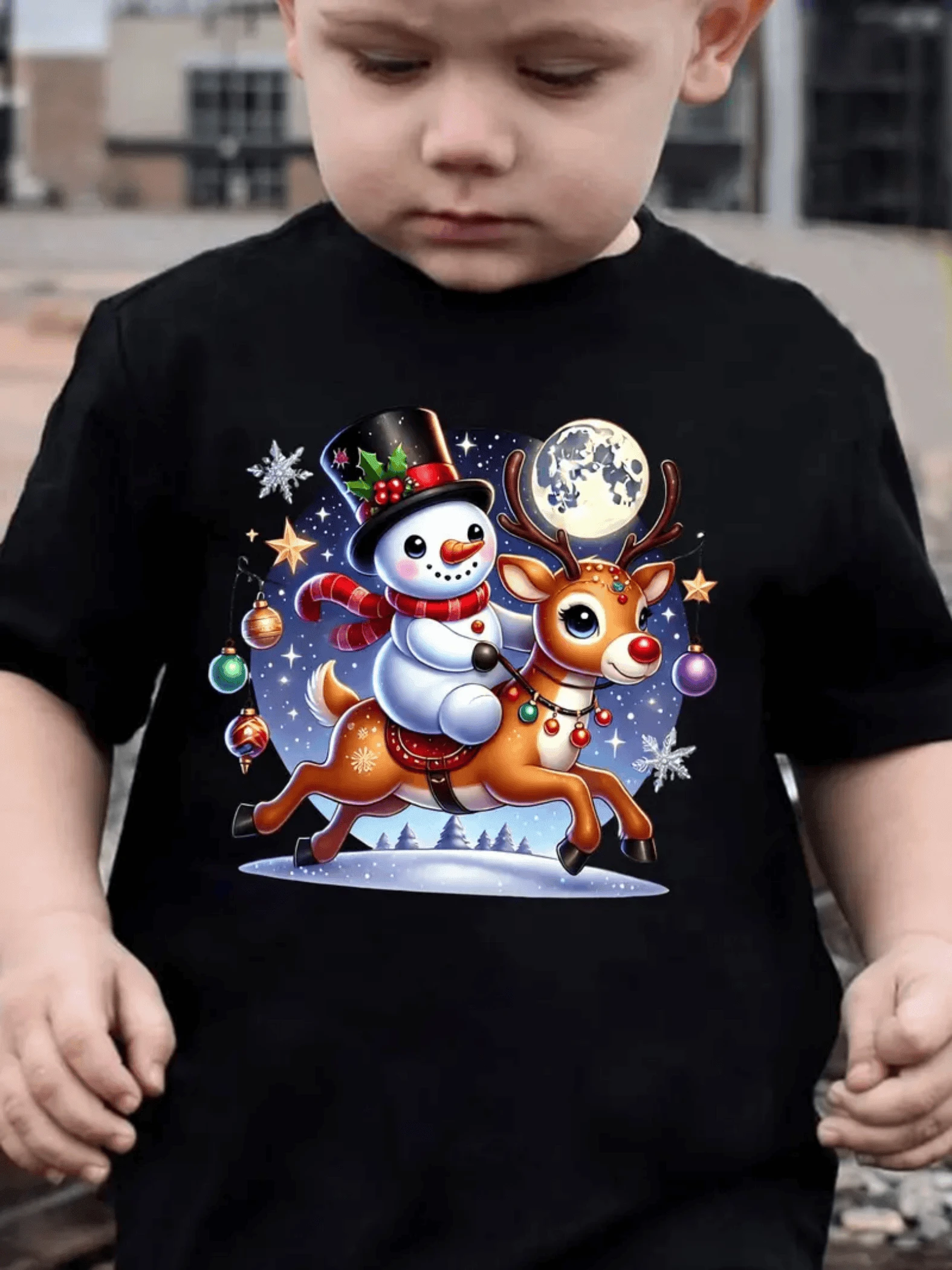 Muñeco de nieve alegre cabalgando junto a un reno bajo la luna rodeado de estrellas y adornos navideños camiseta 100% algodón ropa para niños - Negro - Ver 1