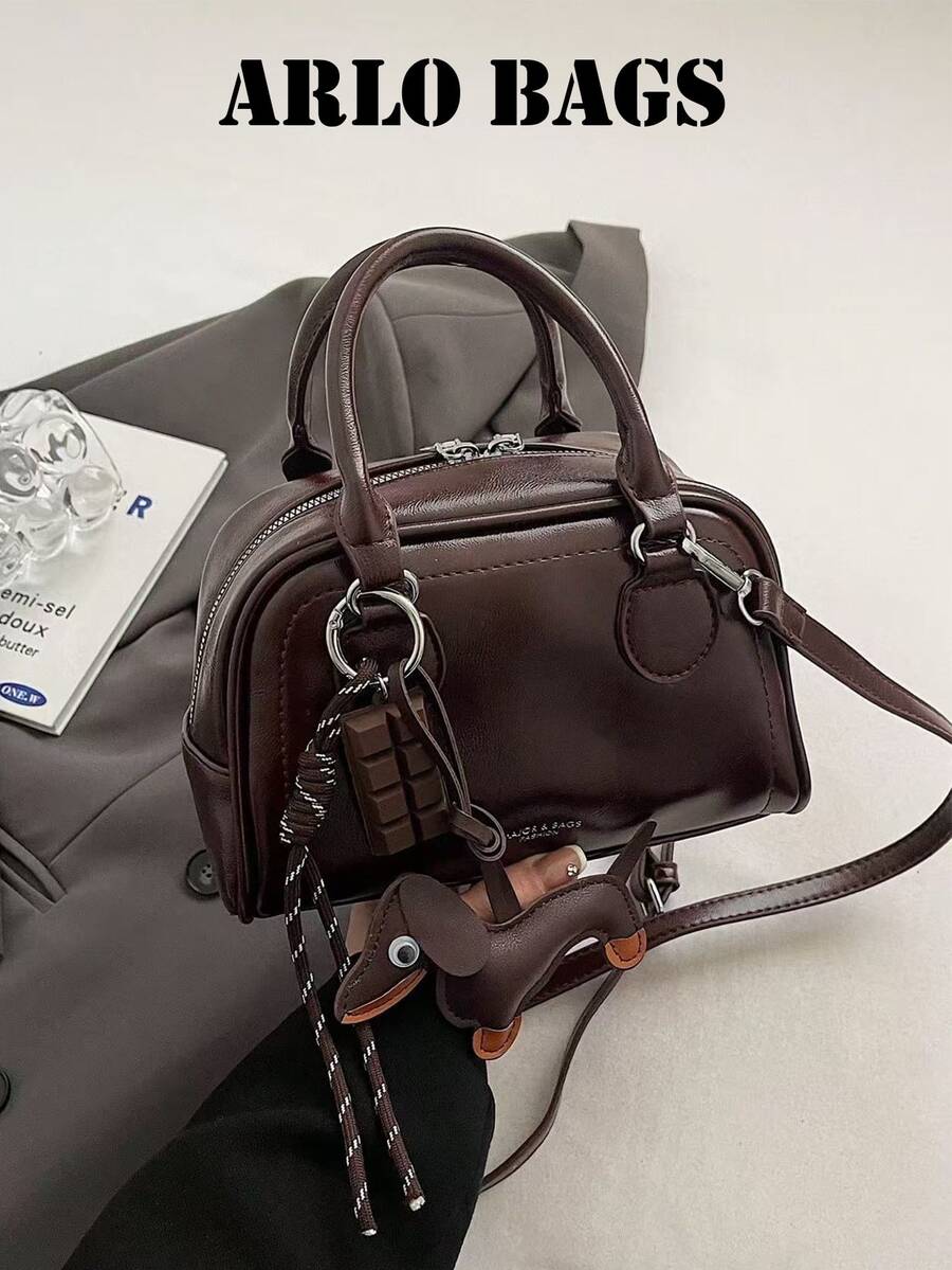 Ce sac de bowling de couleur unie à la mode est en matériau PU, avec une fermeture éclair et un design de lettre, décoré d'un pendentif de chien mignon. Son style minimaliste rétro et sa sensation de haute qualité le font se démarquer. Ce sac à main pour femme convient à un usage quotidien, est polyvalent et est un choix idéal pour les trajets, les courses, les sorties et le travail. C'est un sac pour femme de style vintage.