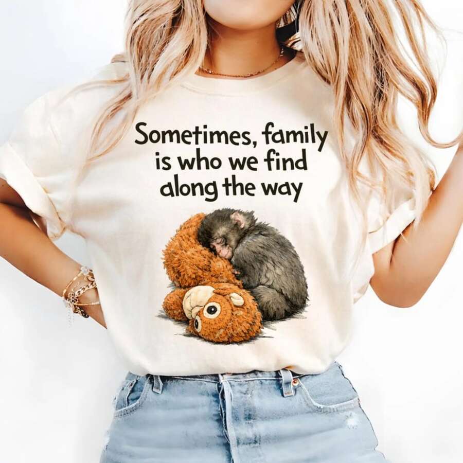 Warm And Realistic Style T-Shirt With A Little Gorilla Cuddling With A Plush Toy While Sleeping Print. Sometimes, Family Is Who We Find Along The Way Text Design. Suitable For Everyday Casual Wear. A Warm, Soothing, Gentle, Heartwarming, Cute, Soft And Adorable Healing Top - White - View 1