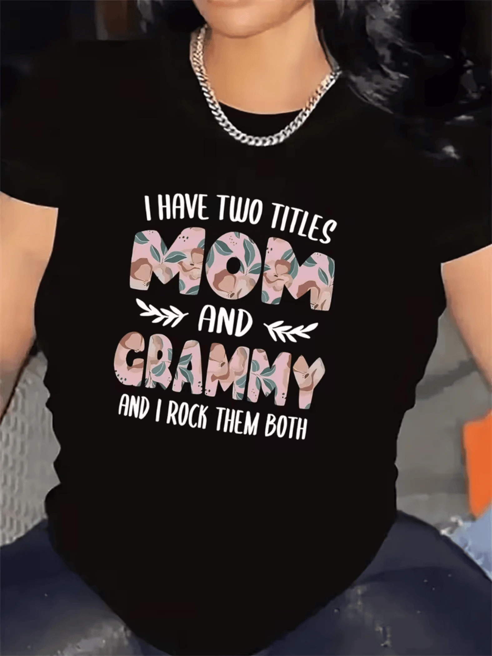 Frase que celebra el orgullo de ser madre y abuela con letras decoradas en flores y hojas que simbolizan amor unión y fortaleza camiseta de mujer casual moderna cómoda para uso diario - Negro - Ver 1
