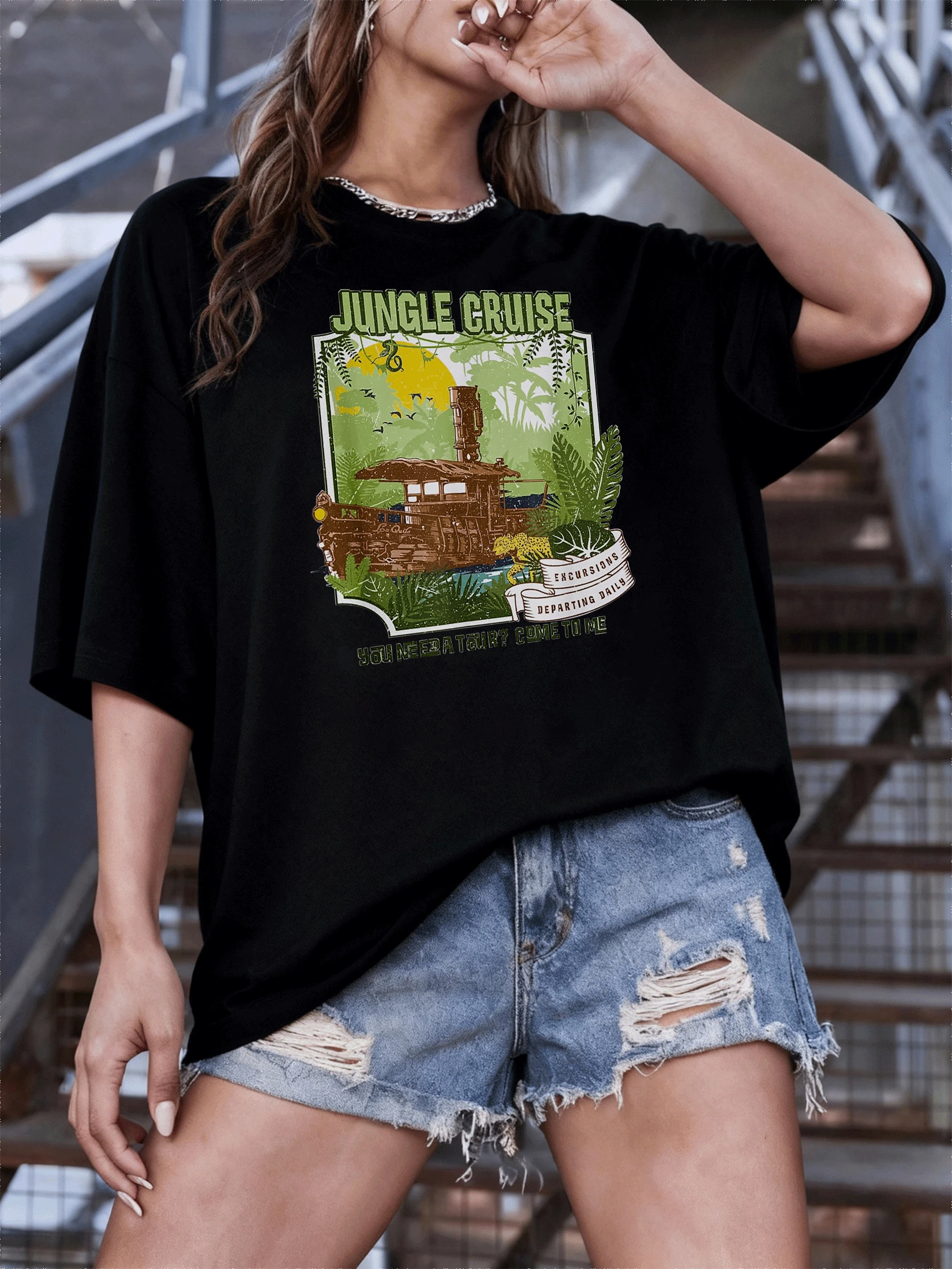 Selva aventurera con barco antiguo navegando entre hojas tropicales bajo un cielo amarillo con aves y un jaguar que representa la energía y la exploración camiseta de mujer casual moderna - Negro - Ver 1