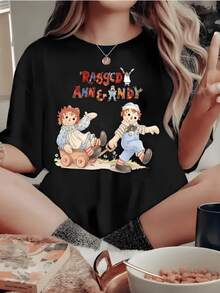 Dos muñecos clásicos representan la amistad pura y la inocencia en un entorno alegre que evoca recuerdos felices y transmite ternura con colores vivos y formas suaves camiseta de mujer casual con estampado artístico vintage - Negro - Ver 1