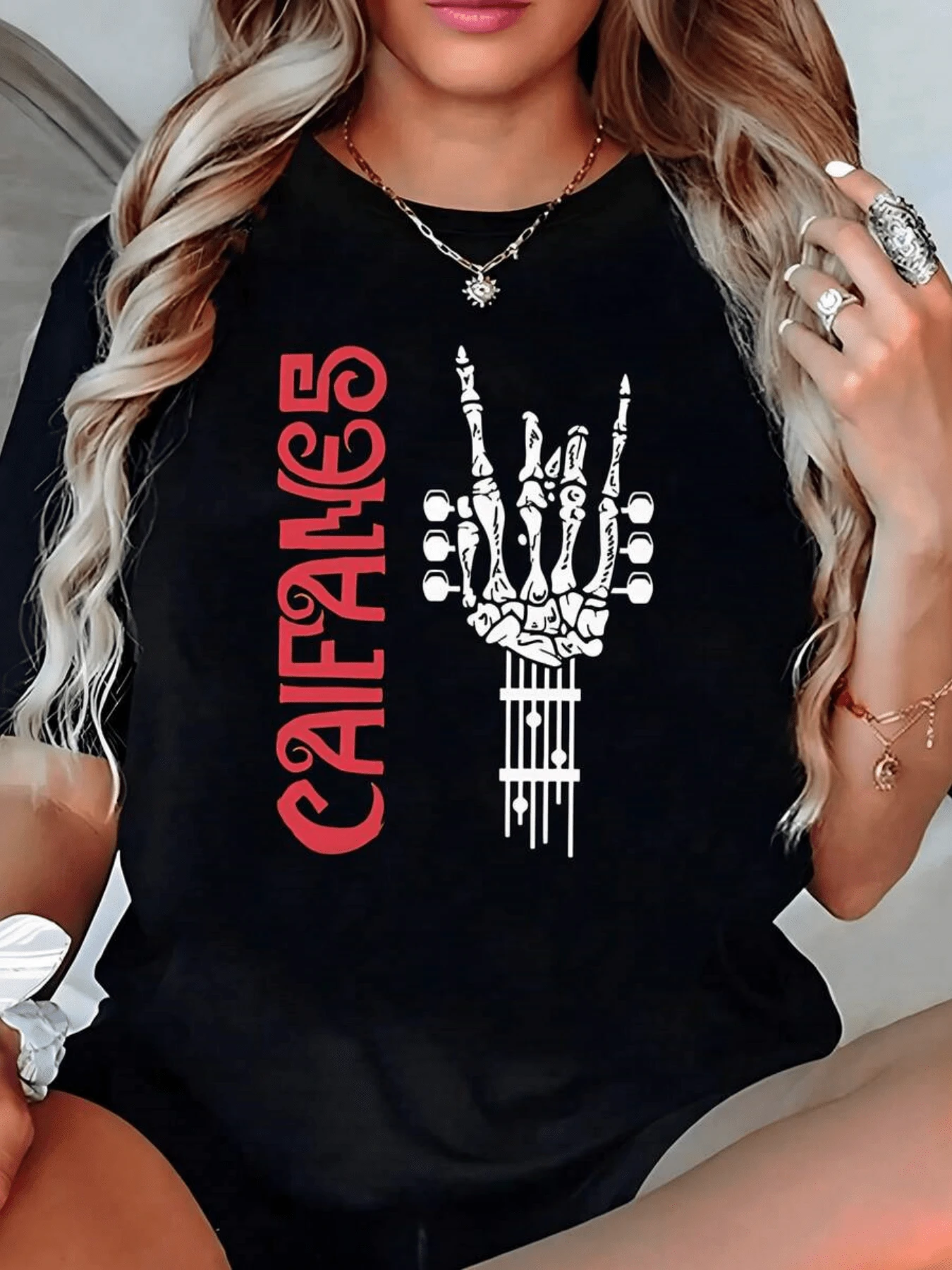 Mano esquelética alzando el gesto de rock sobre cuerdas de guitarra representando la fuerza del espíritu libre y la pasión por la música camiseta de mujer casual moderna para uso diario - Negro - Ver 1