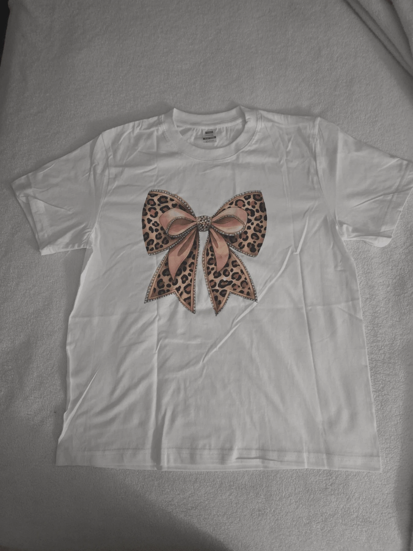 Large Central Bow With Leopard Pattern And Pink Ribbons Symbolizing Elegance, Strength And Femininity In Vibrant Contrast With The White Background. Modern And Comfortable Casual Women's T-Shirt - White - View 1