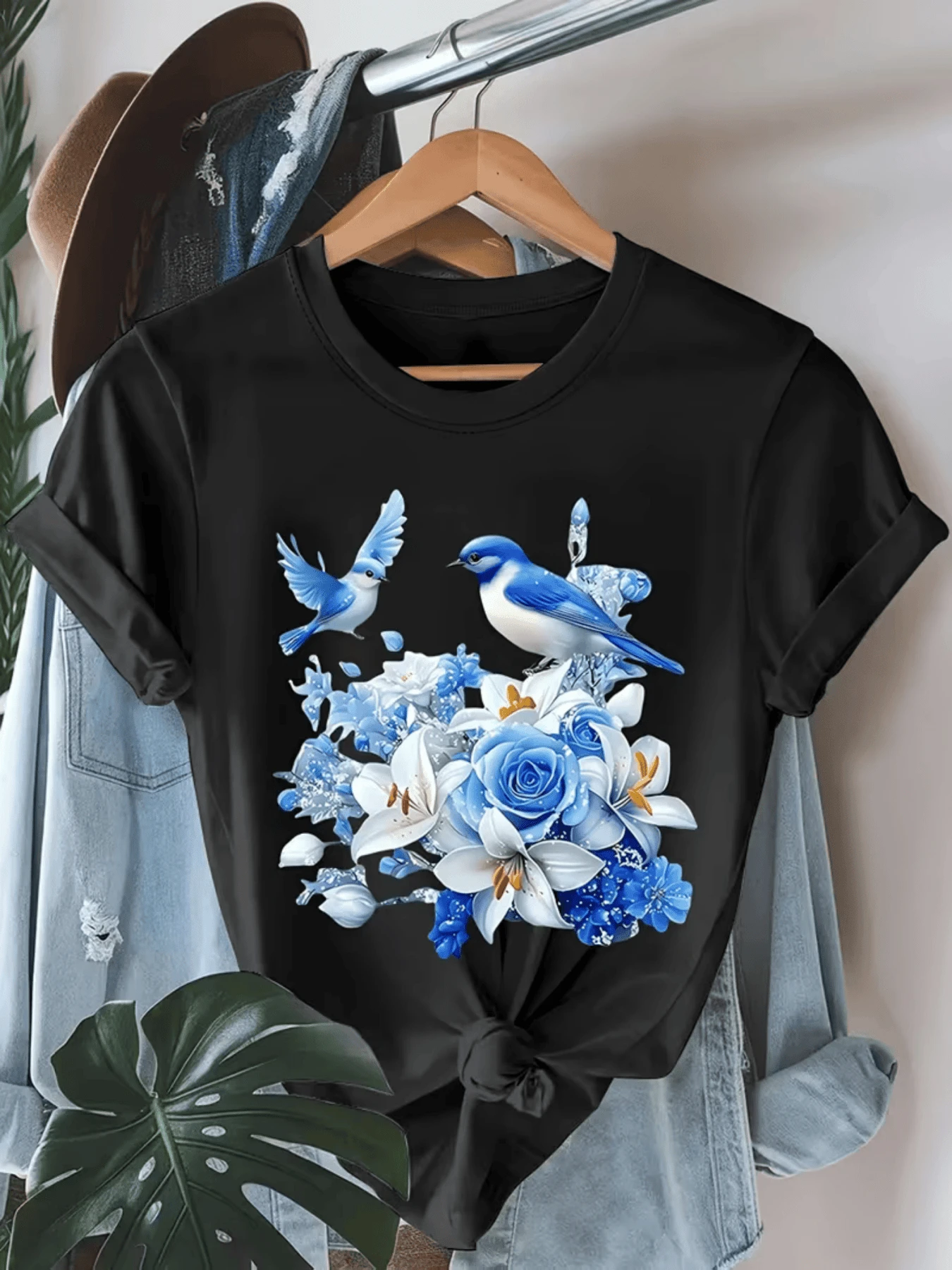 Two Blue Birds Fluttering Above A Bouquet Of Sky-Blue Roses And Lilies Symbolize Freedom, Hope, And Calm In A Harmonious Natural Setting. A Modern And Comfortable Casual Women's T-Shirt For Everyday Wear. - 黑色 - 查看 1