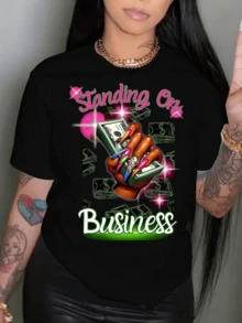 A Woman's Hand With Colorful Nails Holding Banknotes Surrounded By Pink And Green Sparkles Symbolizes Strength, Success, And Empowerment. A Modern, Casual, Comfortable Women's T-Shirt For Everyday Wear. - 黑色 - 查看 1