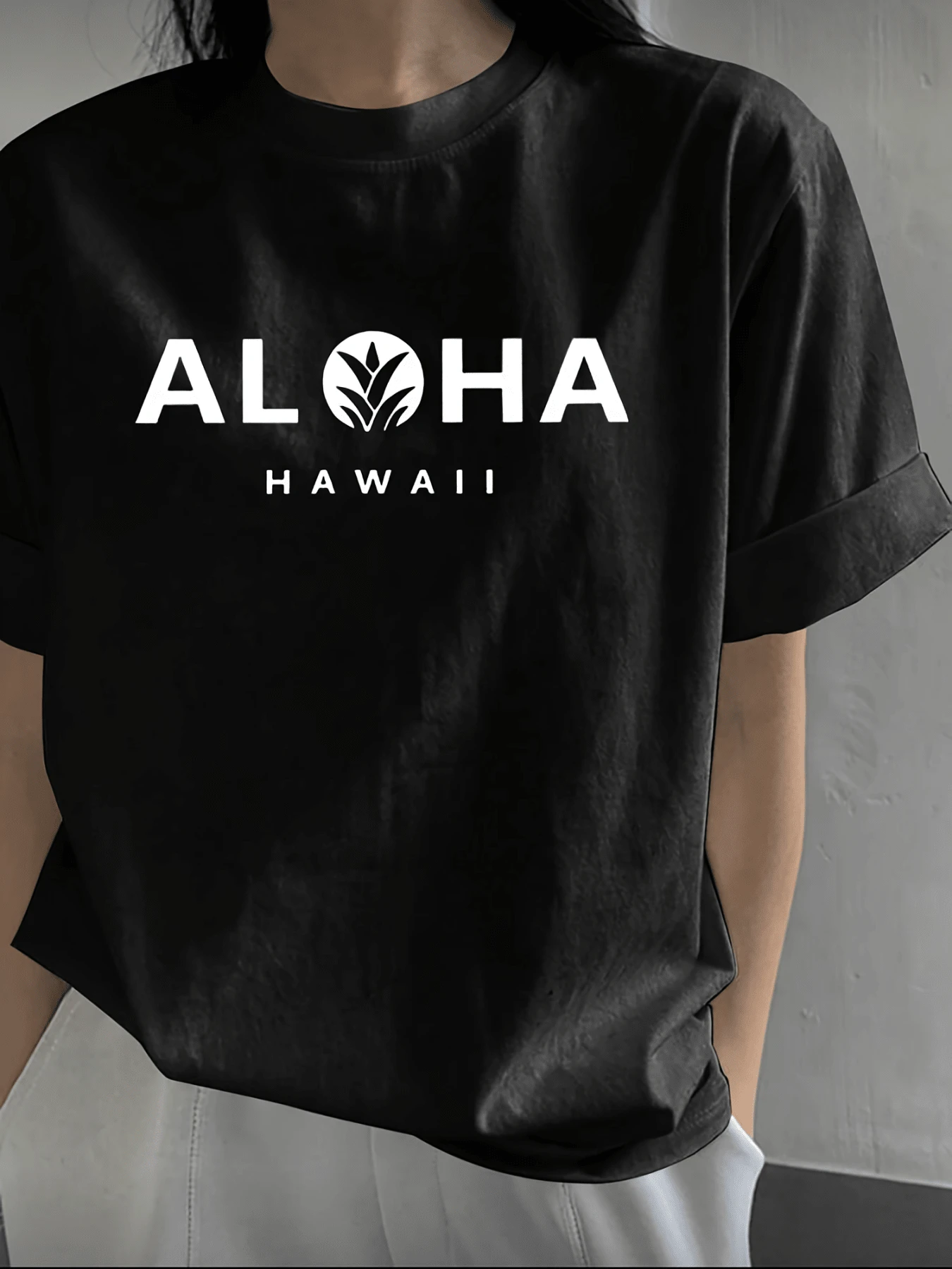 Palabra ALOHA con símbolo inspirado en una hoja tropical que transmite serenidad energía natural y espíritu hawaiano ideal para un estilo casual relajado camiseta de mujer moderna y cómoda - Negro - Ver 1