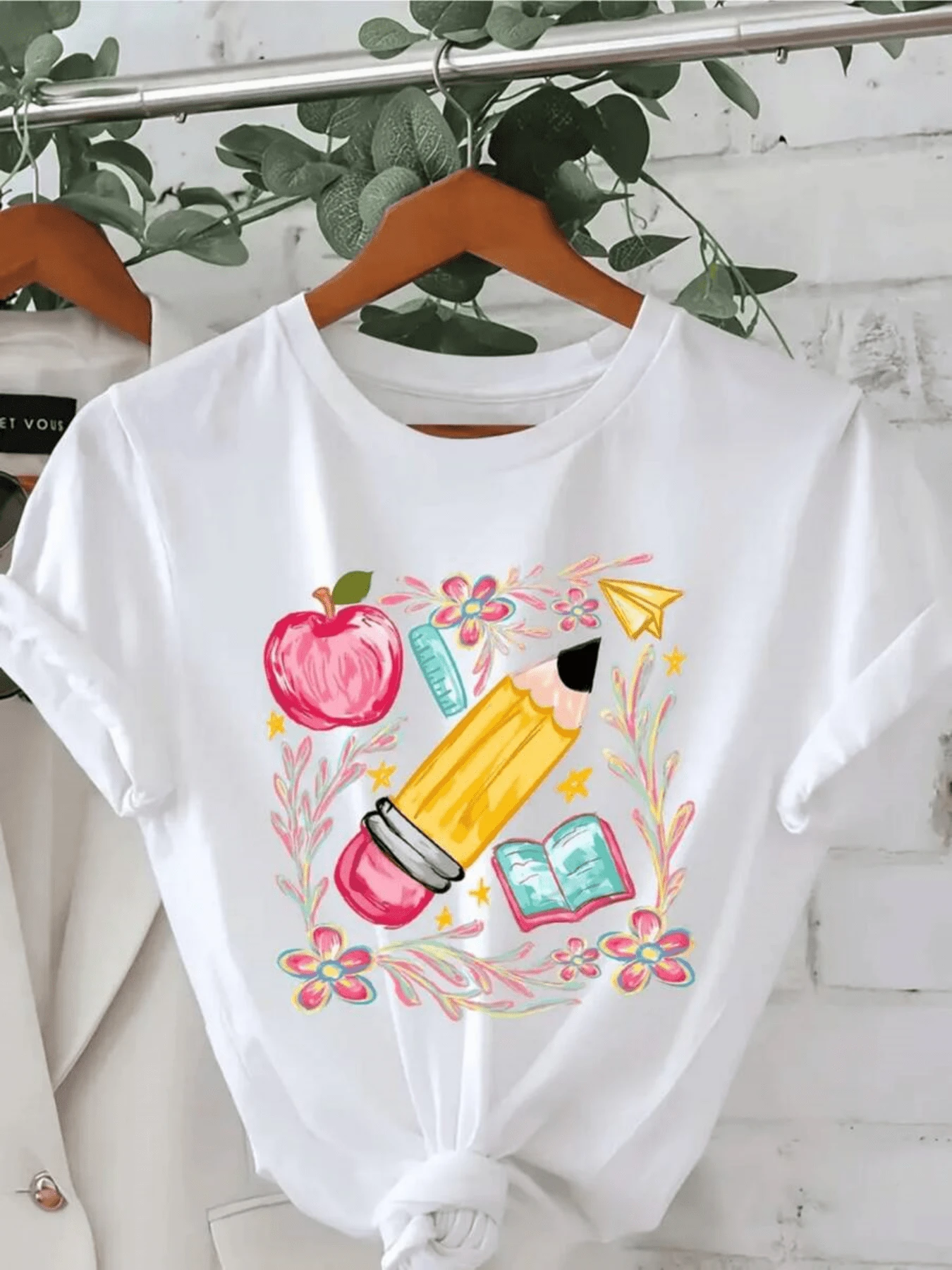 A Giant Pencil Surrounded By Colorful Flowers Next To A Red Apple, An Open Book, And A Paper Airplane Symbolizes Inspiration, Creativity, And A Love Of Learning. A Comfortable And Modern Casual Women's T-Shirt. - 白色 - 查看 1