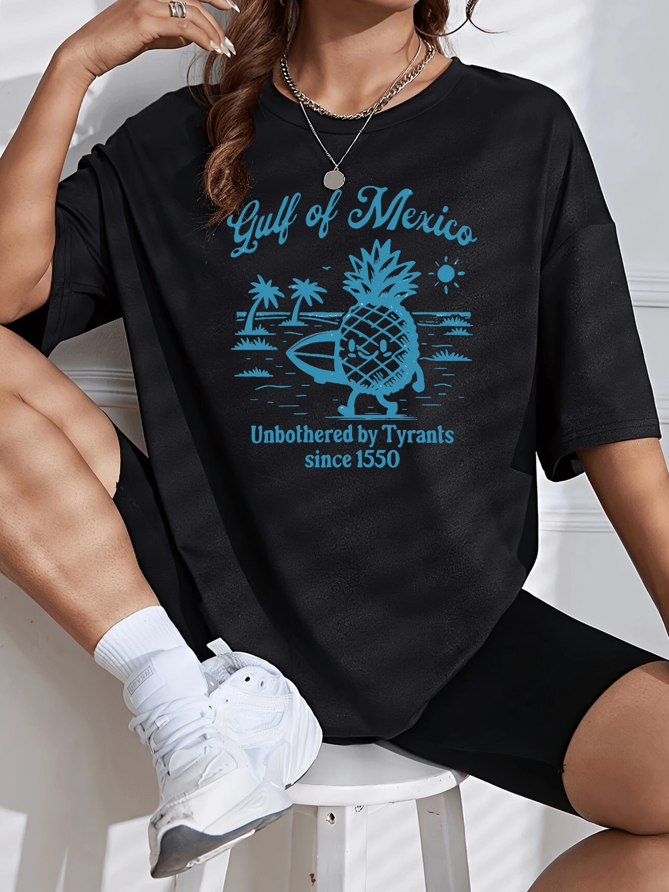 Piña sonriente con tabla de surf rodeada de palmeras bajo un sol brillante representando libertad y alegría junto al mar en el Golfo de México camiseta de mujer casual cómoda y moderna para verano - Negro - Ver 1