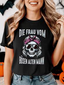 Una figura femenina con pañuelo rosa y gafas oscuras representa fuerza independencia y carácter rebelde con letras alemanas que resaltan actitud audaz y confianza camiseta de mujer casual cómoda para uso diario - Negro - Ver 1