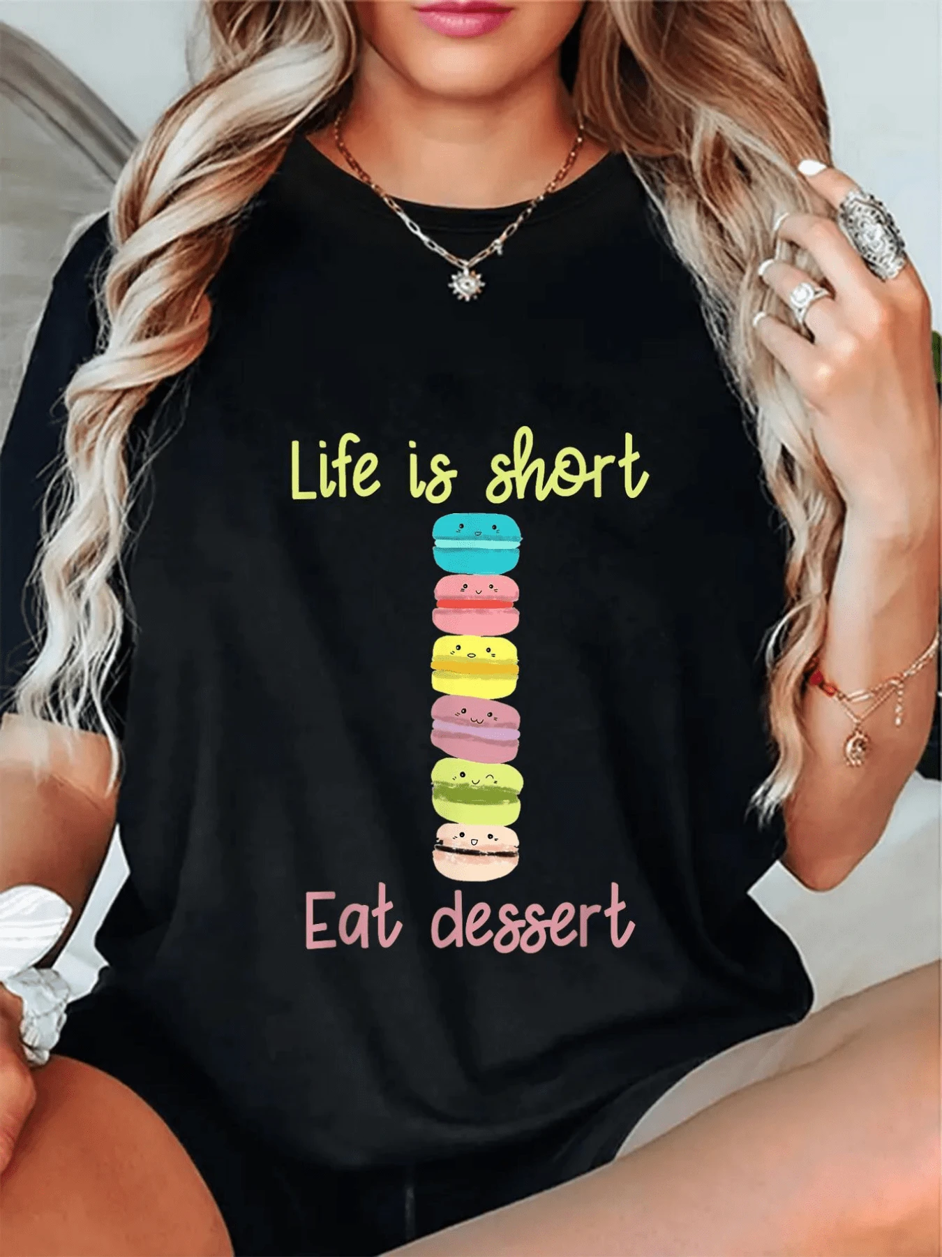Una divertida ilustración que muestra coloridos macarons apilados con caritas alegres acompañados por un mensaje positivo sobre disfrutar los placeres dulces de la vida camiseta de mujer casual moderna para uso diario - Negro - Ver 1