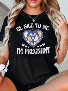 Corazón formado por huellas de pies que simbolizan amor ternura y protección hacia la futura maternidad con mensaje positivo Be nice to me I'm pregnant camiseta de mujer casual cómoda y original - Negro - Ver 1