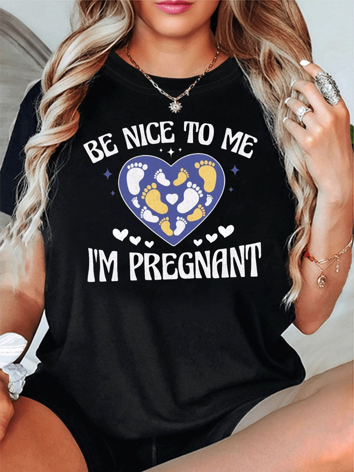 Corazón formado por huellas de pies que simbolizan amor ternura y protección hacia la futura maternidad con mensaje positivo Be nice to me I'm pregnant camiseta de mujer casual cómoda y original - Negro - Ver 1