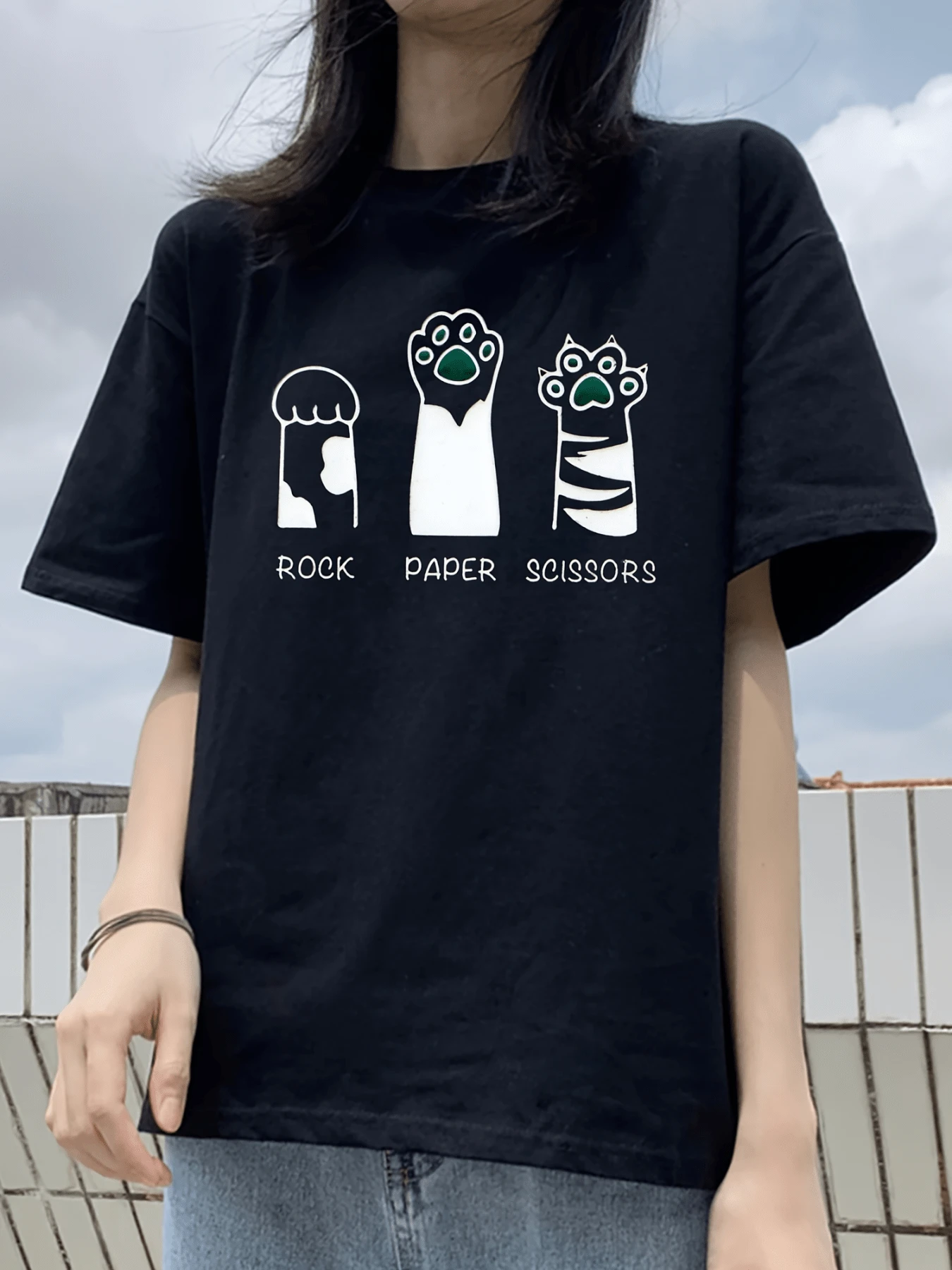 Tres divertidas patas de gato forman los gestos de piedra papel y tijeras representando con humor la convivencia amistosa entre personas y animales mostrando ternura y creatividad camiseta de mujer casual urbana cómoda para diario - Negro - Ver 1
