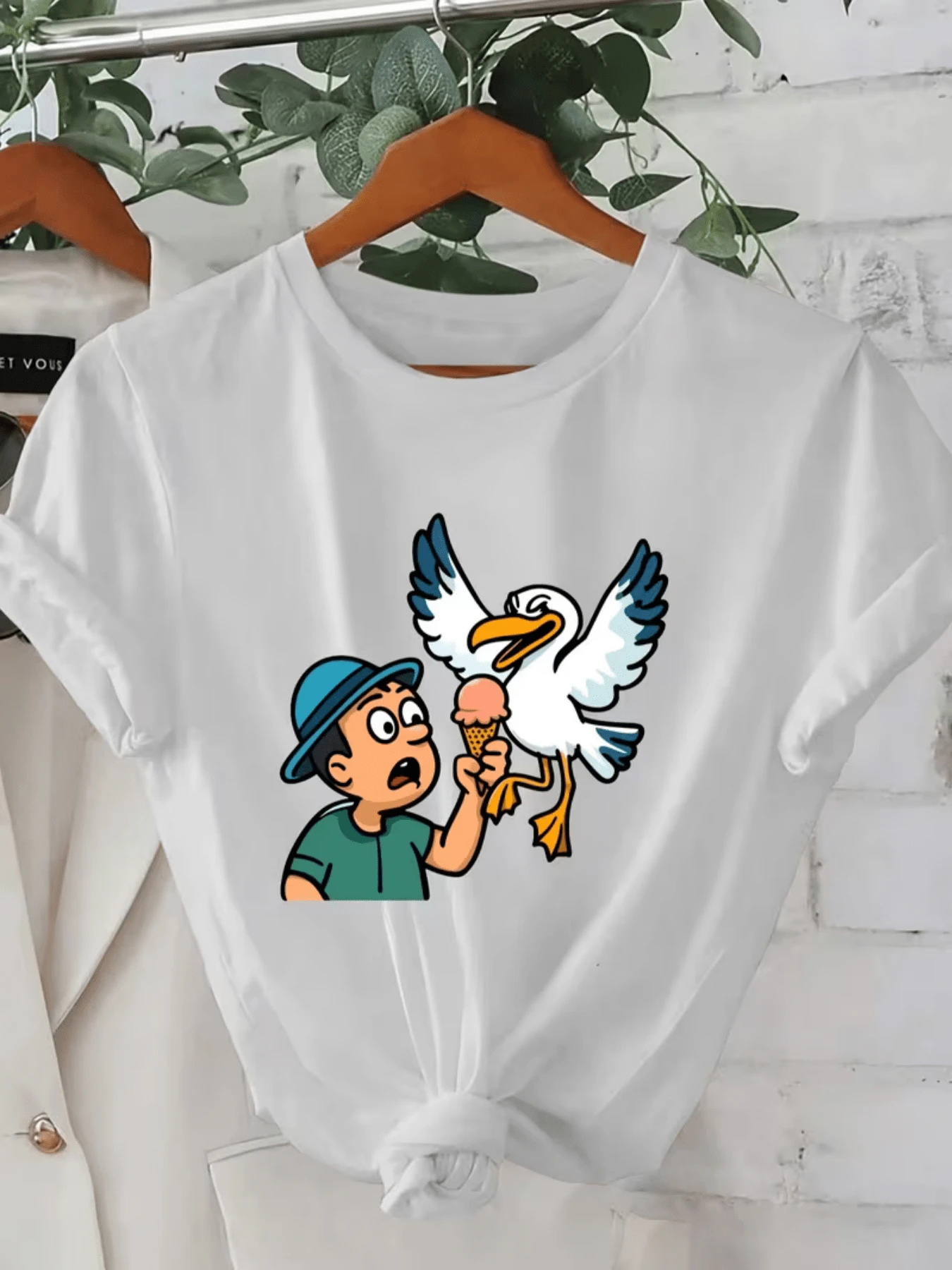 A Fun Drawing Shows A Surprised Young Man As A Mischievous Seagull Snatches His Ice Cream, Reflecting Humor And Summer Energy. A Casual And Comfortable Women's T-Shirt For Everyday Wear. - 白色 - 查看 1