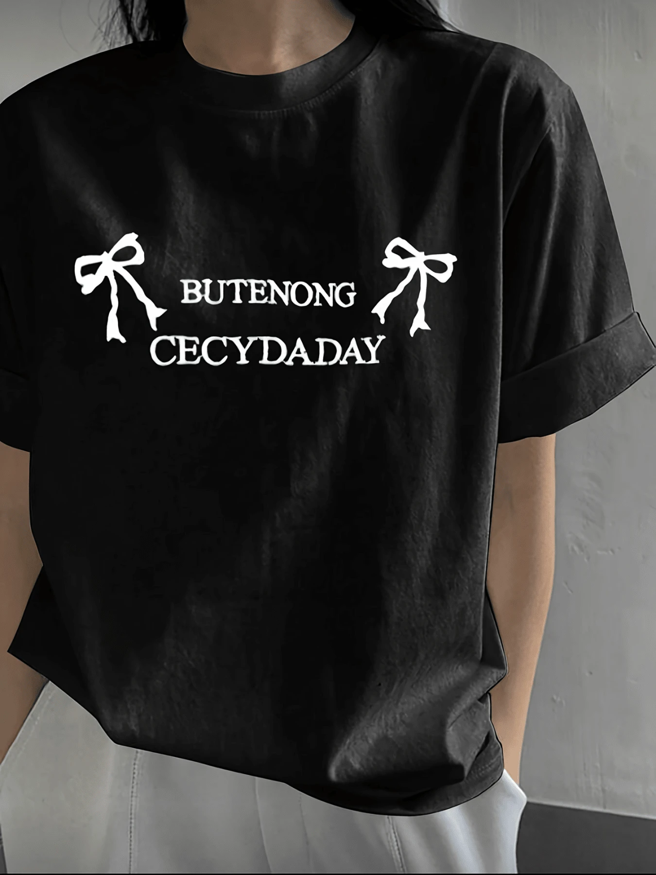 Dos lazos blancos simbolizan ternura y elegancia sobre fondo oscuro transmitiendo un aire de gracia sencilla y estilo moderno perfecto para expresar una actitud relajada camiseta de mujer casual moderna y cómoda - Negro - Ver 1