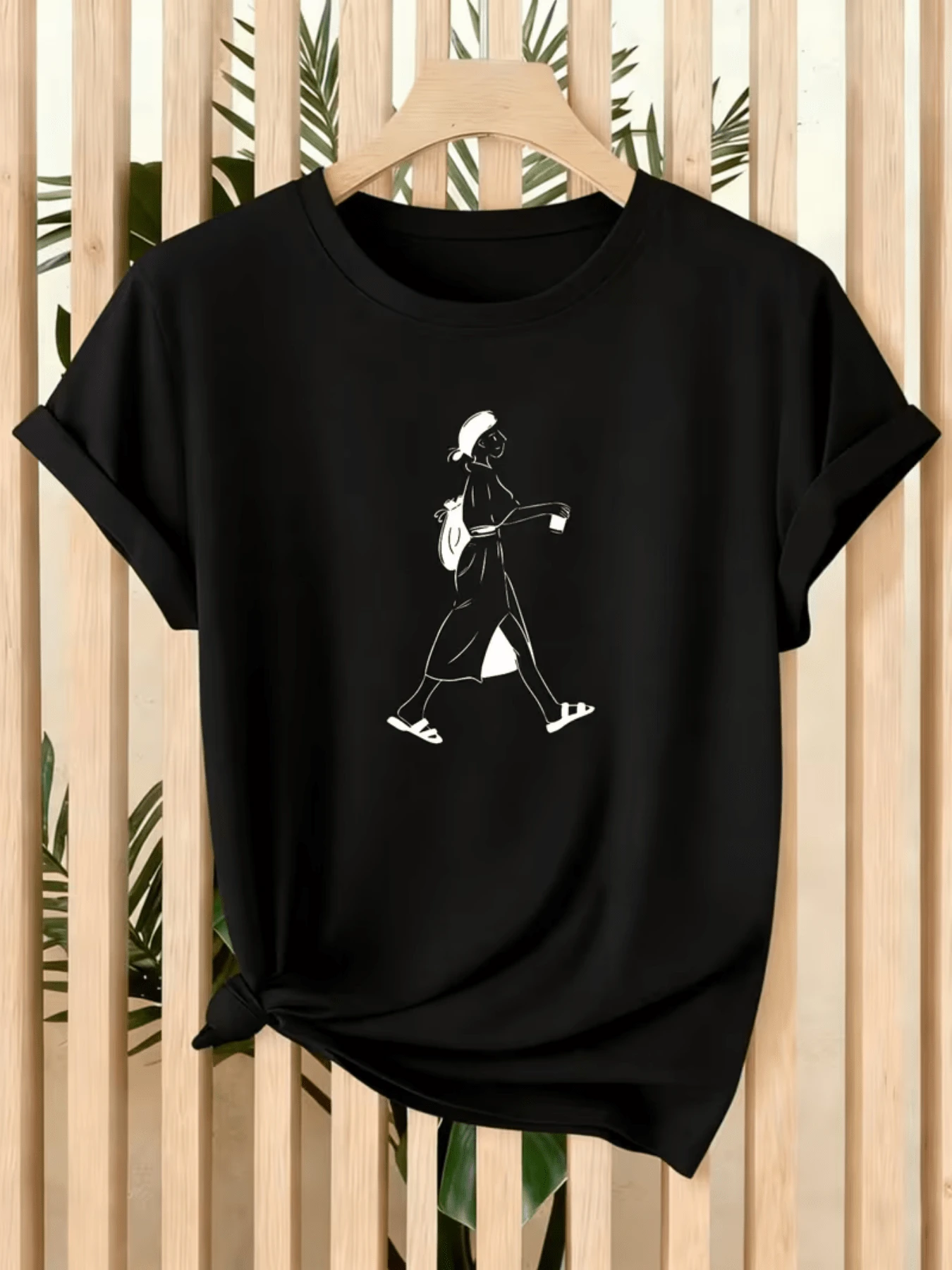 Image Of A Woman Walking Serenely, Holding A Cup And Carrying A Backpack, Symbolizing Freedom, Tranquility, And A Traveler's Spirit. Modern, Comfortable Women's T-Shirt For Everyday Wear. - 黑色 - 查看 1