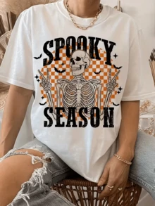Esqueleto sonriente rodeado de murciélagos y cuadros naranjas que evocan una atmósfera divertida y misteriosa perfecta para los días festivos camiseta de mujer casual moderna y cómoda - Blanco - Ver 1
