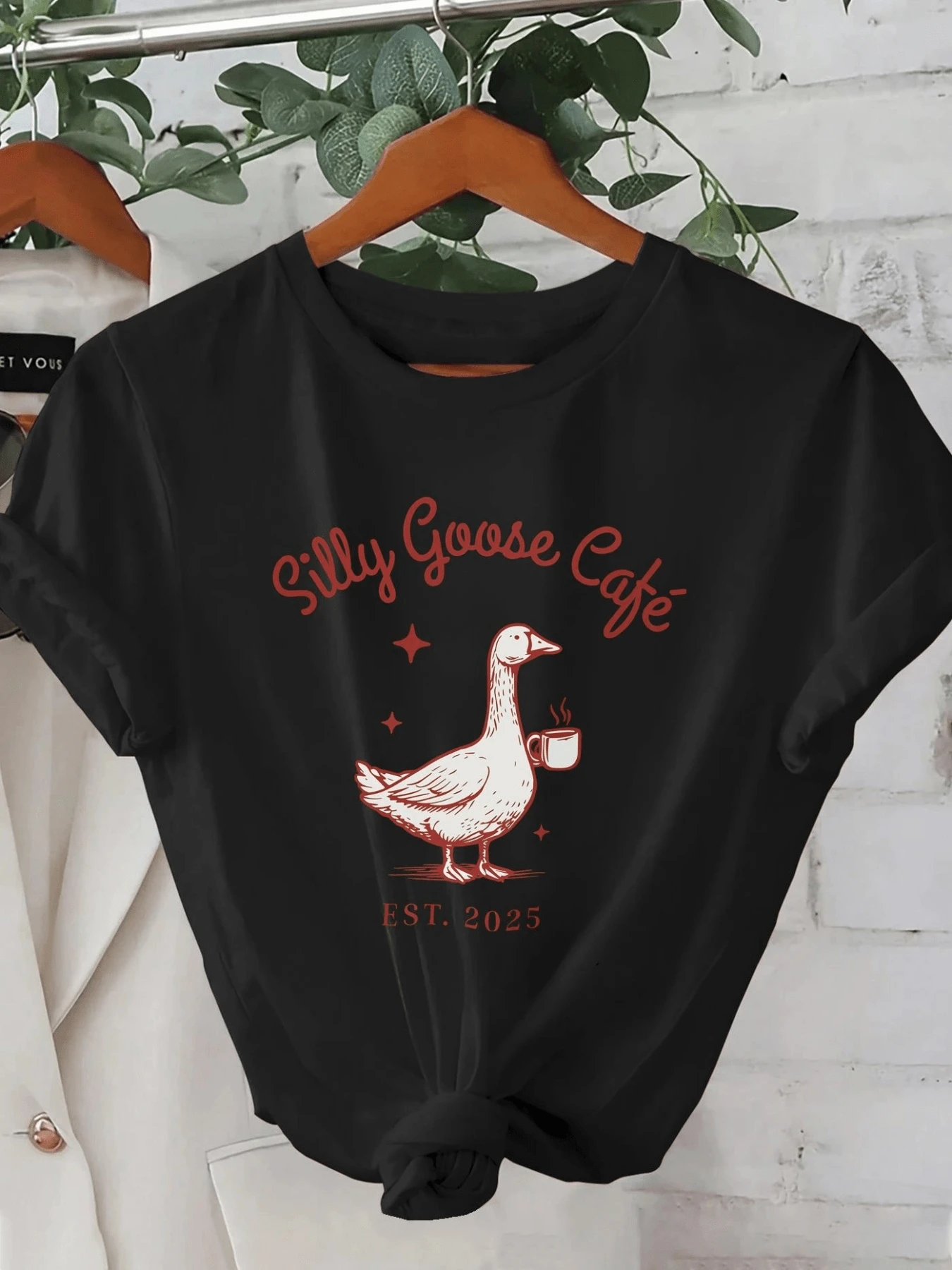 A Playful Goose Holding A Cup Of Coffee Symbolizes The Relaxed Mood Of A Peaceful Morning, Inviting You To Enjoy Warm Moments. A Comfortable, Casual Women's T-Shirt For Everyday Wear. - 黑色 - 查看 1
