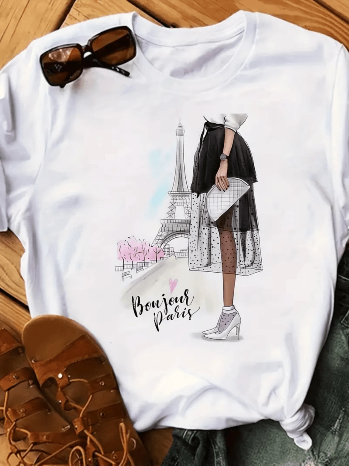 Una mujer elegante con falda de tul y tacones frente a la Torre Eiffel rodeada de flores rosadas que simbolizan un paseo romántico primaveral en París camiseta de mujer casual y cómoda ideal para un look moderno - Blanco - Ver 1