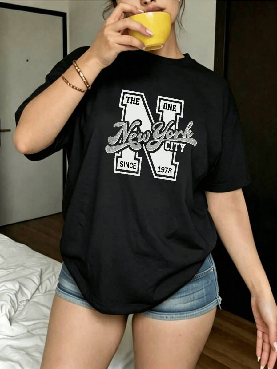 Large Lettering With The Initial N Accompanied By Text That Celebrates The Urban Spirit And Modern Energy Of New York, Evoking Freedom, Casual Style, And Confidence. Comfortable Women's T-Shirt For Everyday Wear - 黑色 - 查看 1