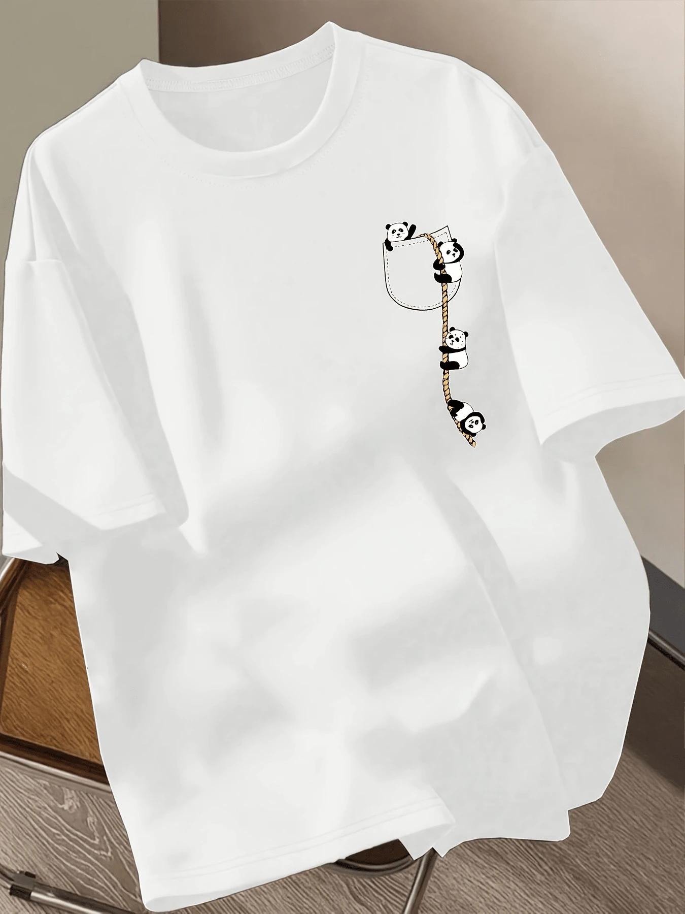 Cute Pandas Climbing A Rope Towards A Small Pocket Symbolize Friendship, Effort, And Joy, Transmitting Positive Energy For Those Seeking Cuteness And Fun. A Comfortable And Modern Casual Women's T-Shirt For Everyday Wear. - 白色 - 查看 1