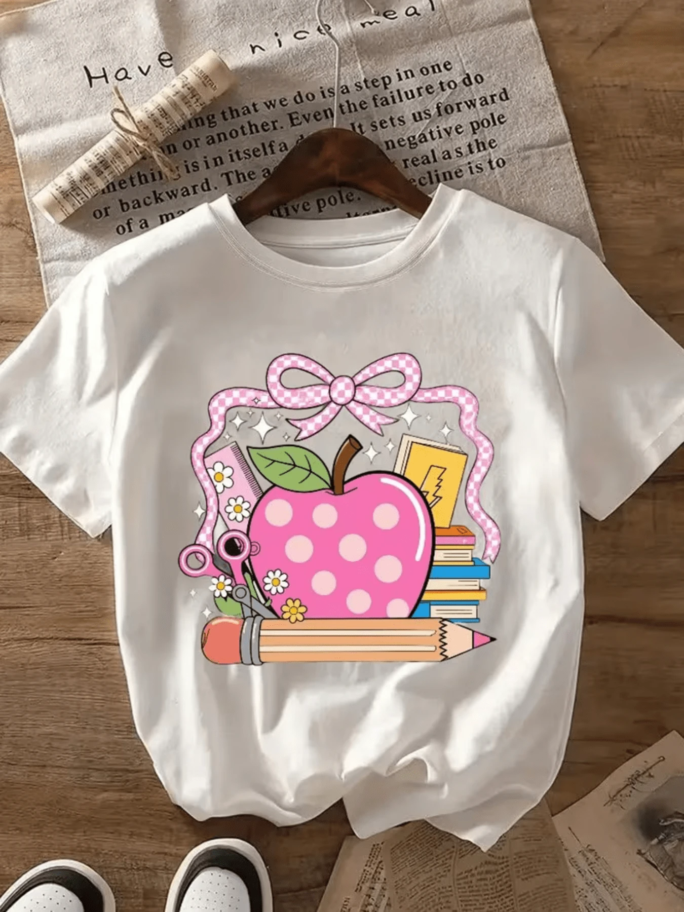 Pink Polka Dot Apple Surrounded By Books, Flowers, Pencil, And Ribbon Symbolizes Knowledge, Creativity, And Positive Energy For Learning. Comfortable Casual Women's T-Shirt For Everyday Wear, Stylish And Cheerful. - White - View 1