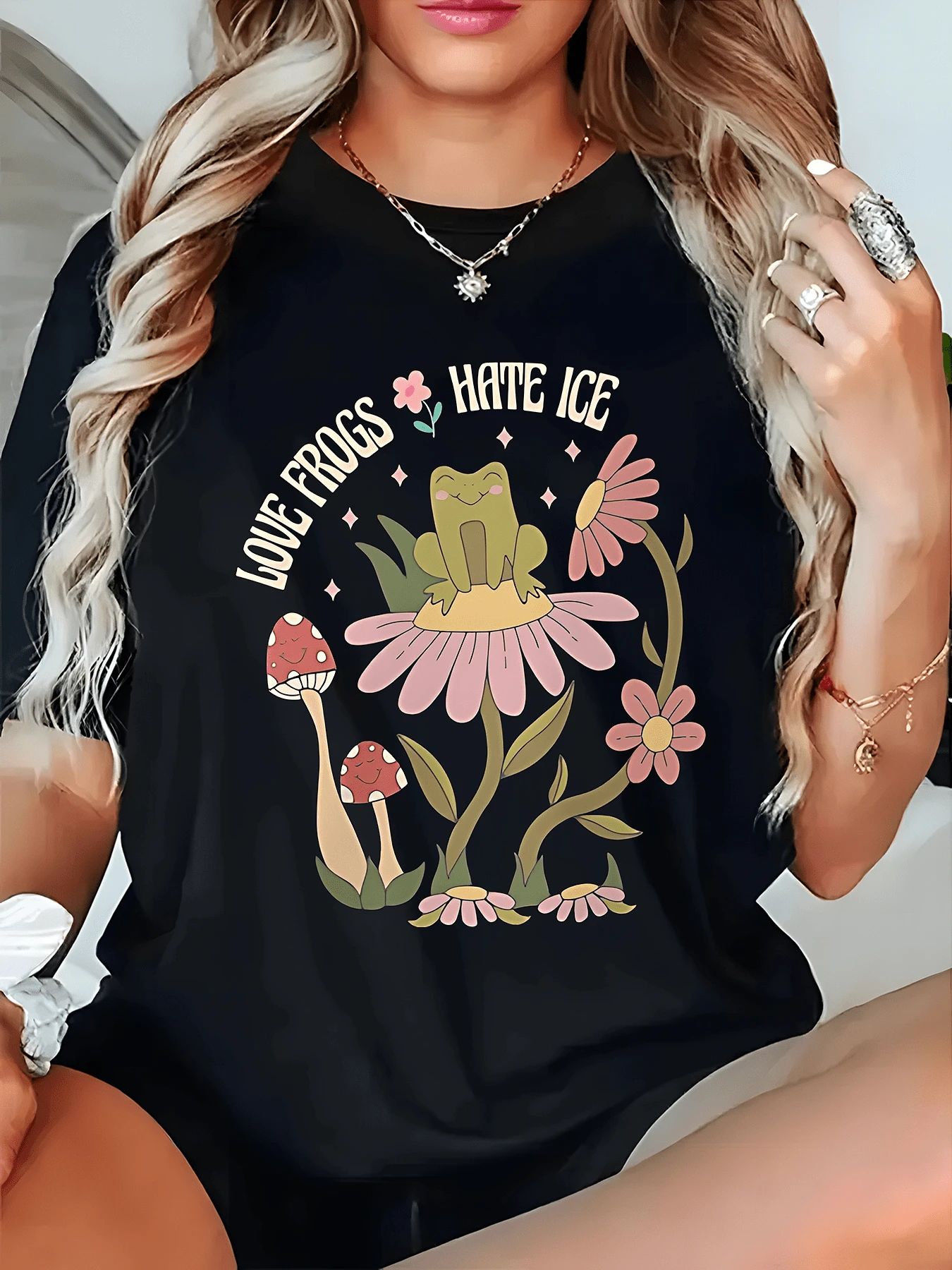 A Cheerful Frog On A Large Pink Flower Surrounded By Mushrooms And Small Flowers Symbolizes Natural Harmony And The Joy Of Living. A Comfortable, Casual Women's T-Shirt For Relaxed Days And Outdoor Adventures. - 黑色 - 查看 1