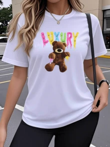 Un estampado que muestra un oso de peluche marrón con detalles coloridos y fondo con letras que evocan diversión juvenil y actitud moderna camiseta de mujer casual cómoda ideal para un look urbano elegante - Blanco - Ver 1