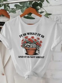 A Raccoon Resting In A Flowerpot Surrounded By Red Flowers Symbolizes The Blend Of Calm And Resignation In The Face Of Difficult Days. A Comfortable, Modern, Casual Women's T-Shirt For Everyday Wear. - 白色 - 查看 1