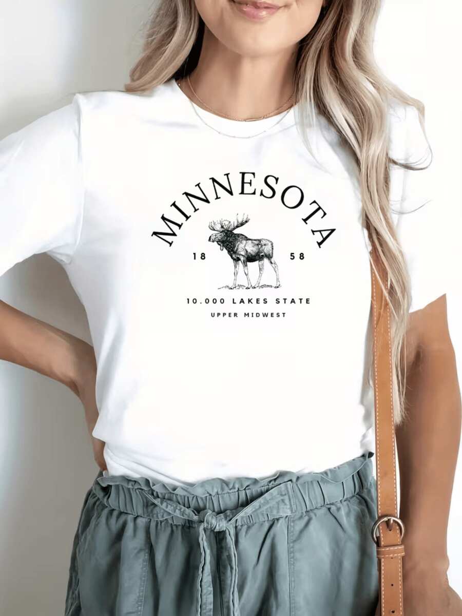 A Majestic Elk Figure Representing The Strength And Calm Of Minnesota's Natural Landscapes, Surrounded By Lettering That Evokes The Serenity Of The State Of Ten Thousand Lakes. A Comfortable, Casual Women's T-Shirt, Ideal For Everyday Wear. - 白色 - 查看 1