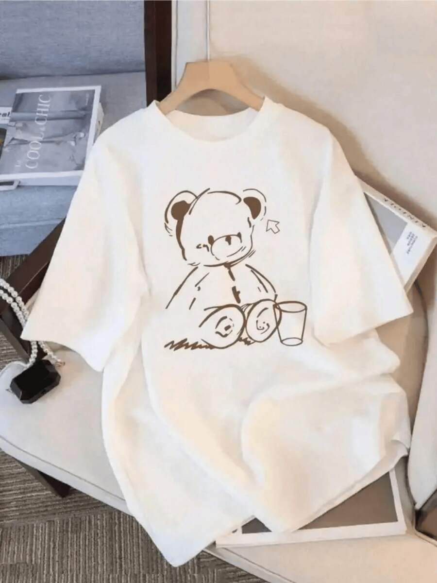 Tierno oso sentado con expresión tranquila junto a un vaso que simboliza un momento de descanso y dulzura reflejando calidez y energía positiva camiseta de mujer casual cómoda para uso diario - Blanco - Ver 1