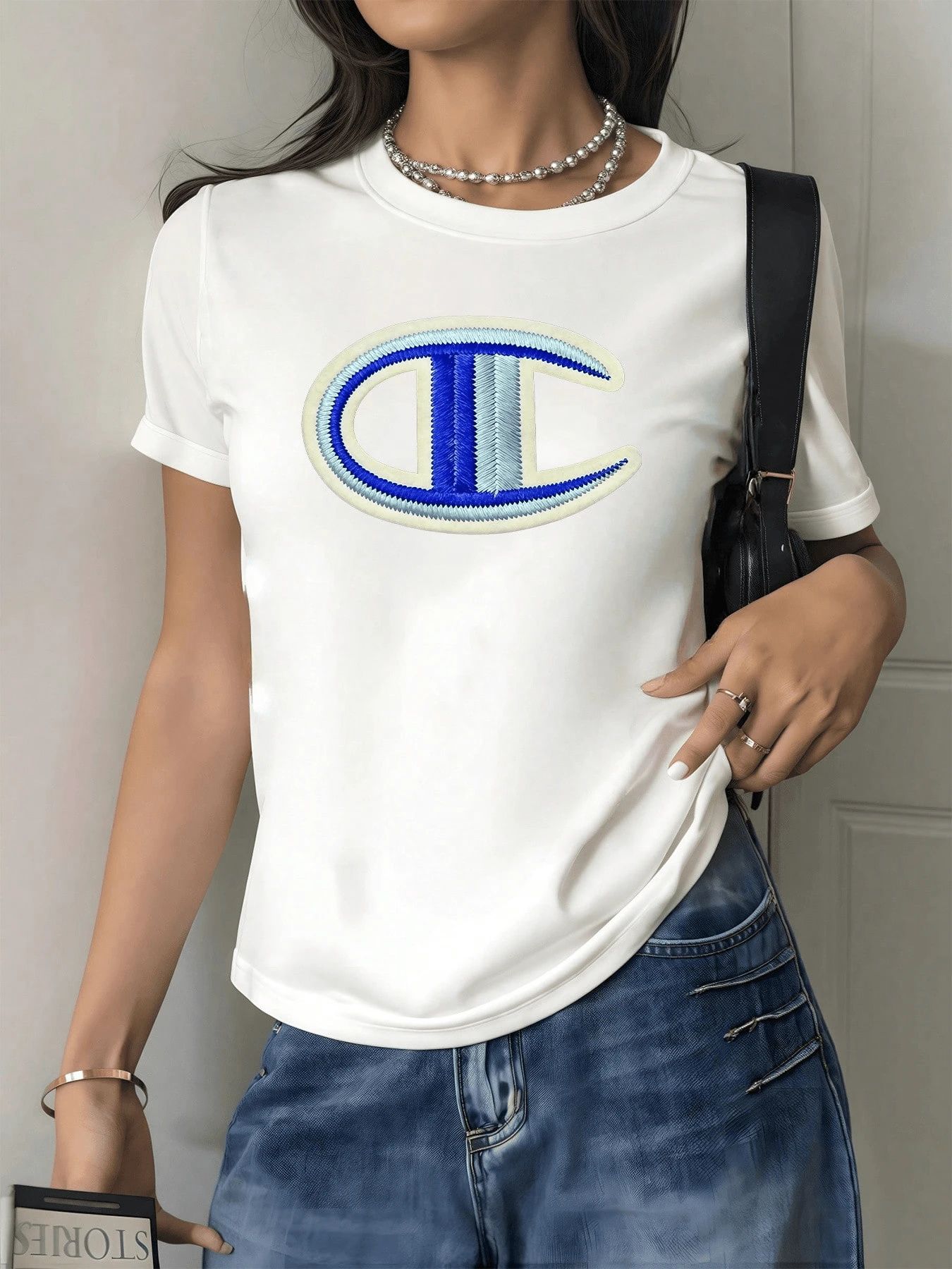 Embroidered Symbol In The Shape Of An Abstract Letter Evoking Balance, Strength, And Modernity In Blue And White Tones. Casual, Comfortable Women's T-Shirt, Ideal For Everyday Wear With An Elegant Touch. - 白色 - 查看 1
