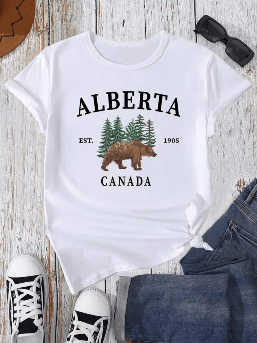 A Majestic Brown Bear Walking Among Green Pines Symbolizes The Strength And Freedom Of Northern Nature And Evokes The Wild Spirit Of Canada. A Modern, Comfortable Women's T-Shirt, Ideal For Casual Wear. - 白色 - 查看 1
