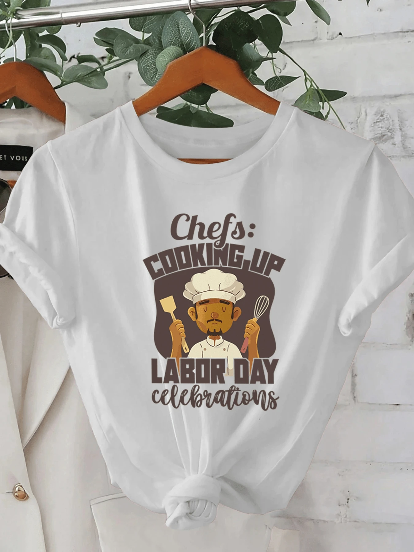A Smiling Chef's Figure Holding Kitchen Utensils Celebrates The Spirit Of Work And Dedication In A Festive Atmosphere With A Motivational Message. A Modern, Comfortable, Casual Women's T-Shirt For Everyday Wear. - 白色 - 查看 1
