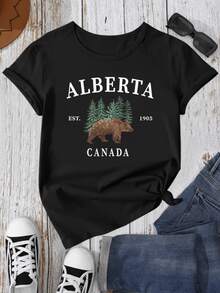 A Majestic Brown Bear Walking Among Green Pines Symbolizes The Strength And Freedom Of Northern Nature And Evokes The Wild Spirit Of Canada. A Modern, Comfortable Women's T-Shirt, Ideal For Casual Wear. - 黑色 - 查看 1