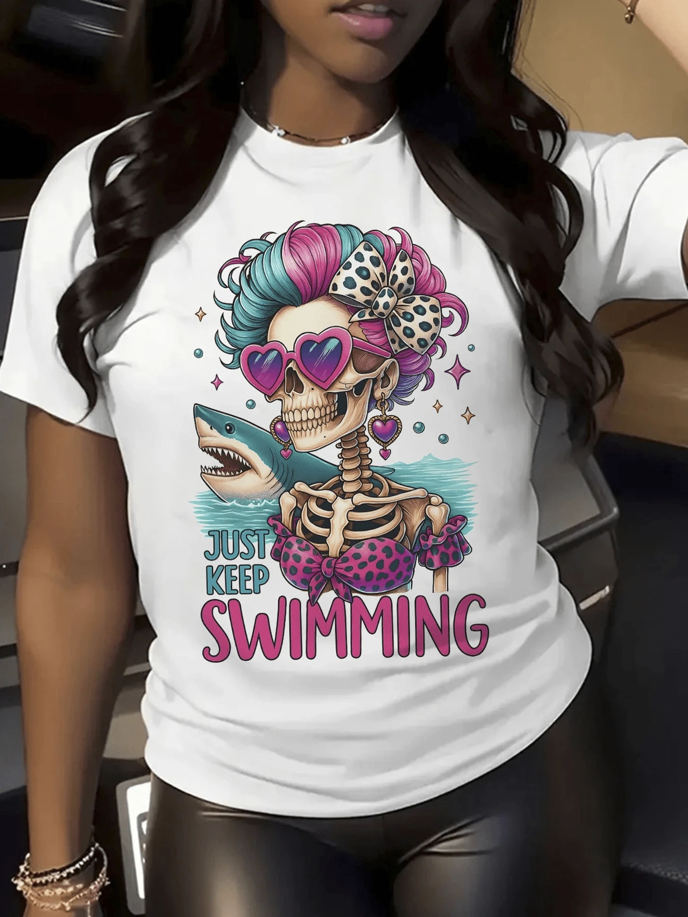 Calavera femenina con gafas de corazón cabello azul y rosa lazo de lunares y un tiburón que simboliza fuerza y valentía frente al mar camiseta de mujer casual moderna divertida - Blanco - Ver 1