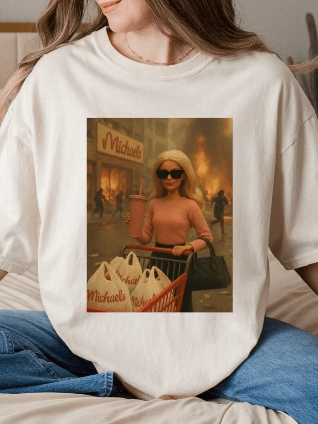Una figura femenina con estilo moderno empuja un carrito lleno de bolsas mientras detrás se observa una escena intensa de fuego que simboliza la calma y fuerza ante el caos camiseta de mujer casual cómoda para uso diario - Blanco - Ver 1