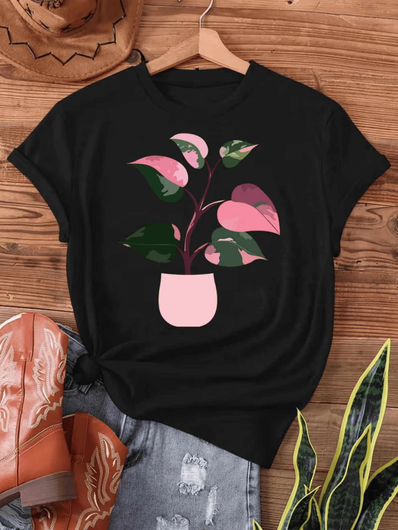 Planta con hojas variegadas en rosa y verde vibrante en maceta rosa simboliza crecimiento y belleza natural ideal para amantes de la botánica y decoración hogar camiseta de mujer cómoda versátil y moderna. - Negro - Ver 1
