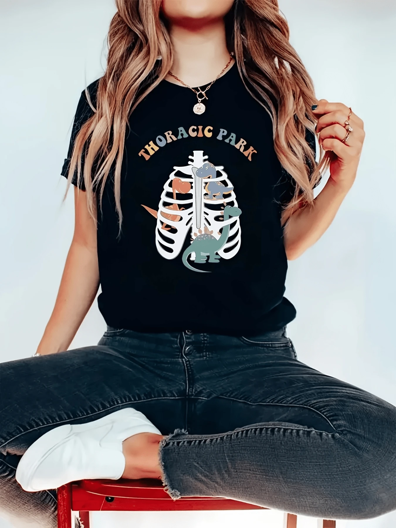 Un conjunto divertido de dinosaurios sonrientes explora una caja torácica humana formando una escena única que combina ciencia y humor en perfecta armonía camiseta de mujer casual ideal para regalar o usar en ocasiones relajadas - Negro - Ver 1