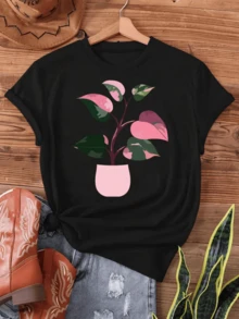 Planta con hojas variegadas en rosa y verde vibrante en maceta rosa simboliza crecimiento y belleza natural ideal para amantes de la botánica y decoración hogar camiseta de mujer cómoda versátil y moderna. - Negro - Ver 8