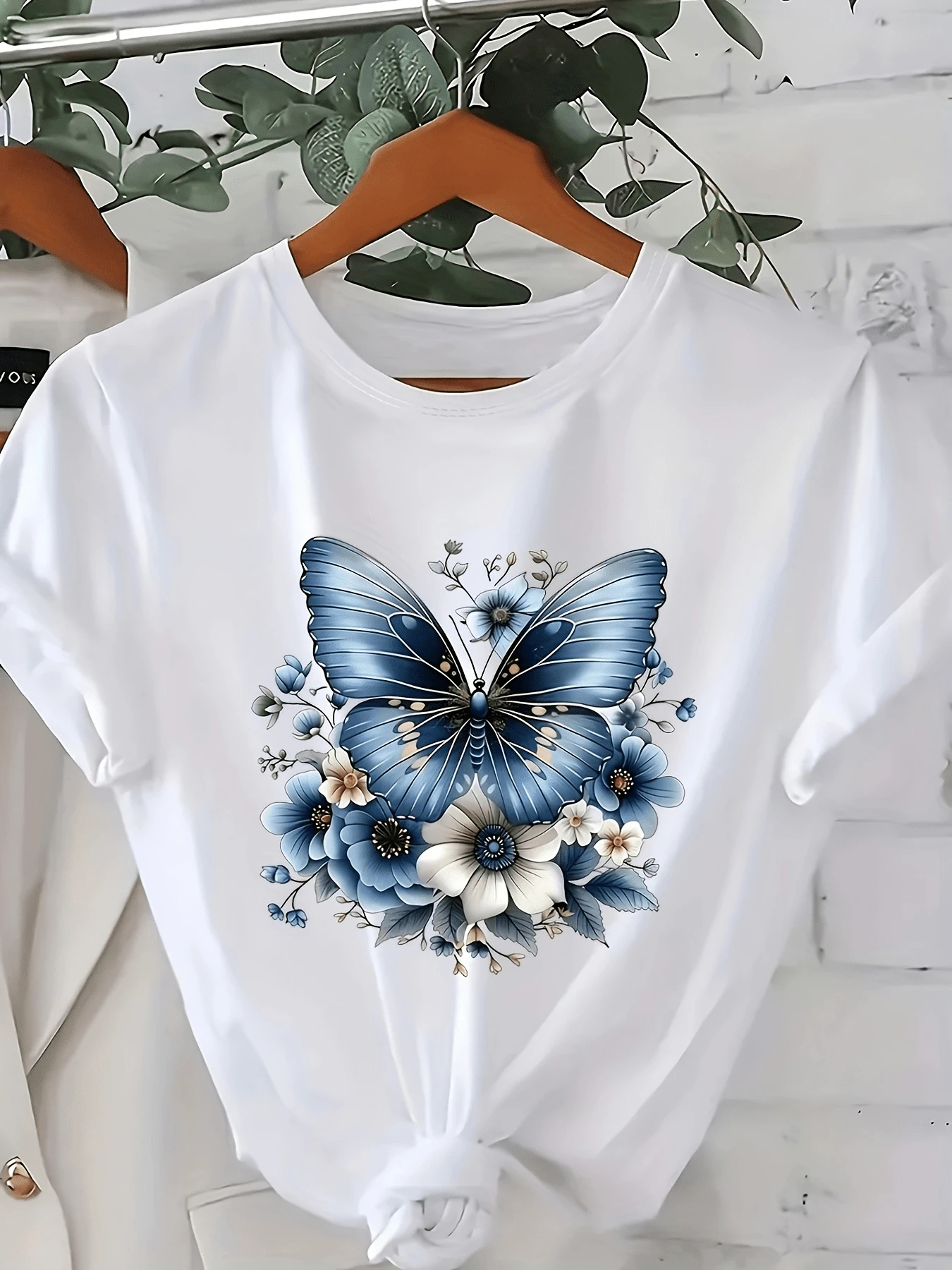 Mariposa azul rodeada de flores delicadas que simbolizan libertad esperanza y conexión con la naturaleza camiseta de mujer moderna cómoda para uso diario - Blanco - Ver 1